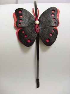 a black and red butterfly hair clip on a headband with a pearl in the center