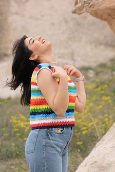 a woman standing in front of a rock and looking up at the sky with her eyes closed