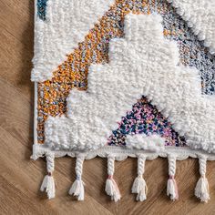 a multicolored rug with tassels and fringes on the bottom is laying on a wooden floor