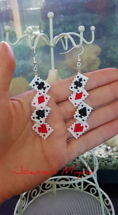 the hand is holding two pairs of beaded earrings