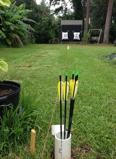 several arrows stuck in a cup on the grass