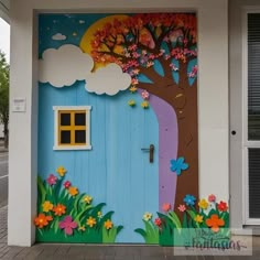 a painted door on the side of a building with a tree and flowers in it