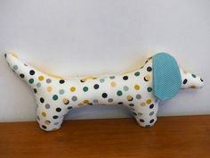 a stuffed dog with polka dots on it's body and a blue disc in its mouth