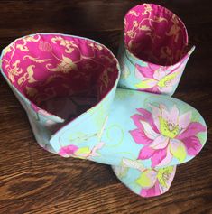 three flowered paper cups sitting on top of a wooden table next to each other