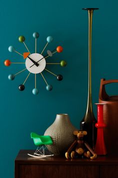 there is a clock on the wall next to vases and other items in front of it