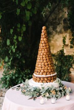 a wedding cake made out of nuts on top of a table with candles and greenery