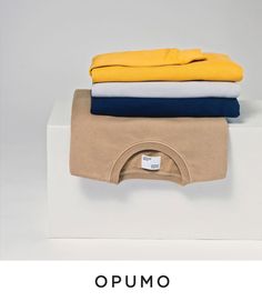 three folded shirts on top of each other with the words opumo above them