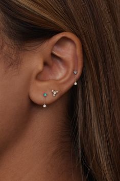 a woman's ear is shown with three different colored stones on the top and bottom