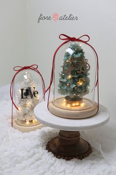 two snow globes sitting on top of a white table covered in lights and decorations