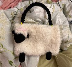 a white sheep purse sitting on top of a bed