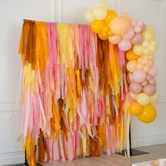 there are many balloons and streamers hanging from the wall in front of the table