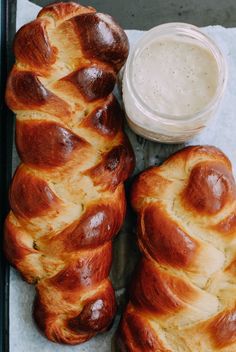 two loaves of bread sitting on top of a pan next to a jar of cream