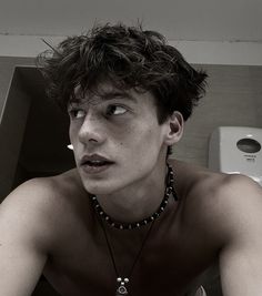 a shirtless young man sitting in front of a toilet