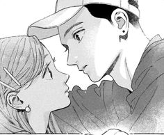 a man and woman kissing each other in front of a baseball cap on their head