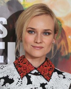 a woman with blonde hair wearing a black and white shirt, red bow tie and earrings