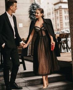 a man and woman holding hands while walking down stairs