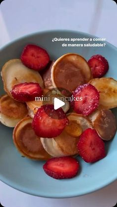 a blue bowl filled with sliced bananas and strawberries on top of a white table