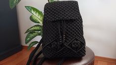 a crocheted black purse sitting on top of a wooden table next to a plant