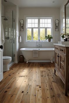 a bathroom with wood flooring and white bathtub next to a sink under a window