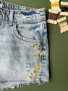 a pair of jeans with flowers on them next to some pins and clothes pegs