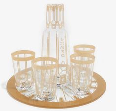 a set of six glasses and a bottle on a tray