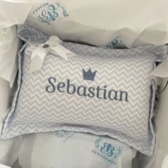 a blue and white pillow with the word sebastian on it in a box