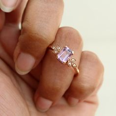 a woman's hand holding a ring with an amethorate and diamonds on it