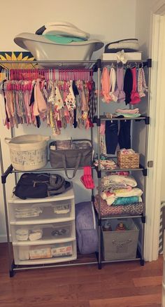 an organized closet with clothes, diapers and other items on shelves next to a door