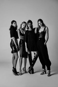 four women standing next to each other posing for a black and white photo in high heels