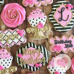 decorated cookies with pink, black and white icing on a wooden table in the shape of cupcakes