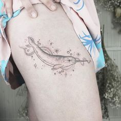 a woman's thigh with a tattoo of a whale and stars on the side