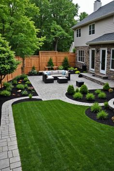 an outdoor patio with seating and landscaping in the back yard, surrounded by green grass