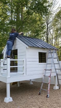 a man is on top of a white house with a ladder to climb up the roof