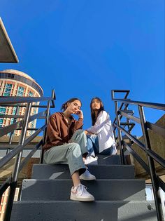 two young women sitting on the steps in front of a building