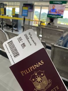 a close up of a person holding a red and yellow passport in an airport terminal