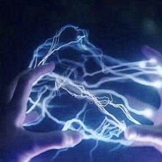 two hands holding something in the dark with some lightening on it's fingers