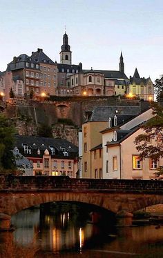 a bridge crossing over a river in front of a city with buildings on the hill