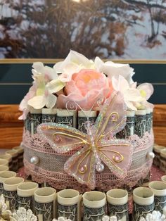 there is a cake decorated with lace and flowers on the table next to many cups