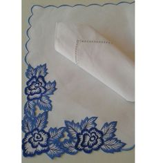 a white and blue table cloth with flowers on it, next to a napkin that is folded in the shape of a flower