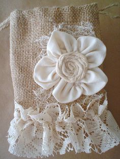 a white flower is sitting on top of a piece of burlock fabric with lace