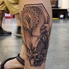 a woman's leg with a skeleton and flowers tattoo on her left calf area