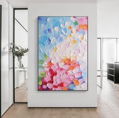 an abstract painting hangs on the wall in a white room