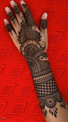 a woman's hand with henna tattoos on her left arm and the top half of