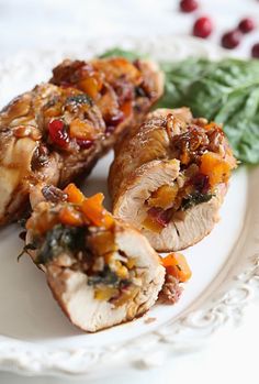 three pieces of meat on a plate with spinach and cranberry toppings