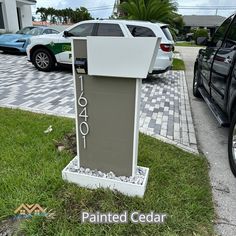 a parking meter sitting on the side of a road next to cars parked in front of it