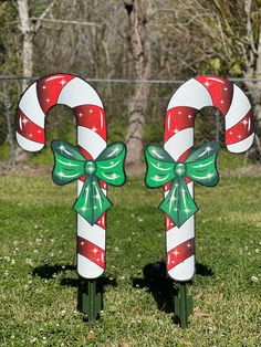 two christmas candy canes on top of each other in the grass with trees in the background