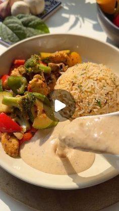 a white plate topped with rice and veggies next to a bowl of vegetables