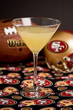 a martini glass filled with yellow liquid next to a football