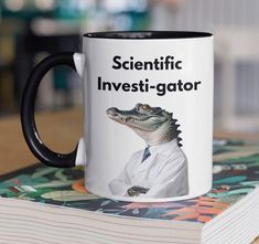 a black and white coffee mug sitting on top of a table next to a book