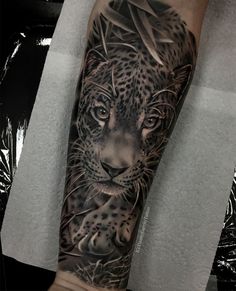 a man's arm with a black and grey tattoo of a leopard on it